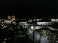 Bilde av Akershus festning i forgrunnen, med Oslo rådhus i bakgrunnen, nattbelysning.