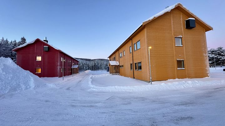 To nye trebygninger i snødekt landskap.