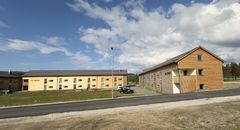 To bygninger med moderne design ved en vei under en blå himmel.