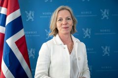 Kvinne ser i kamera med det norske flagget ved siden av