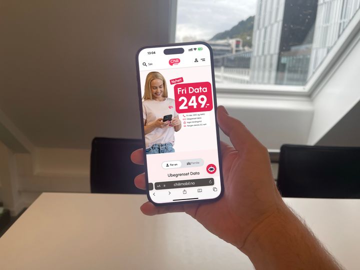En person holder en mobiltelefon som viser en nettside med et tilbud om fri data til 249 kroner fra Chilimobil