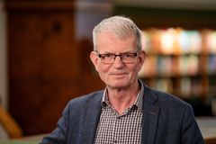 Mann med briller foran en bokhylle