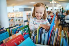 Et barn ser gjennom fargerike bøker i et bibliotek.