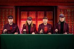 Fire uniformerte personer med stempel sitter bak en skranke på Nasjonalbibliotekets scene.