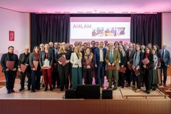A group of people standing on a stage, holding certificates. A screen in the background displays "AI4LAM."