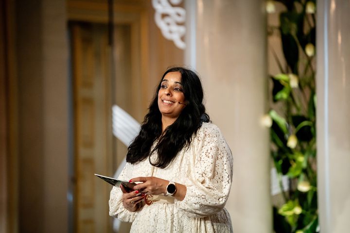 Kvinne%20som%20smiler%20og%20holder%20et%20manuskript.