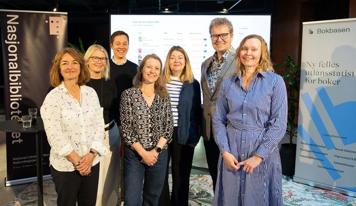 En gruppe på syv personer står foran bannere for Nasjonalbiblioteket og en ny statistikkløsning.