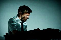 Mann spiller piano i blågrønt lys.