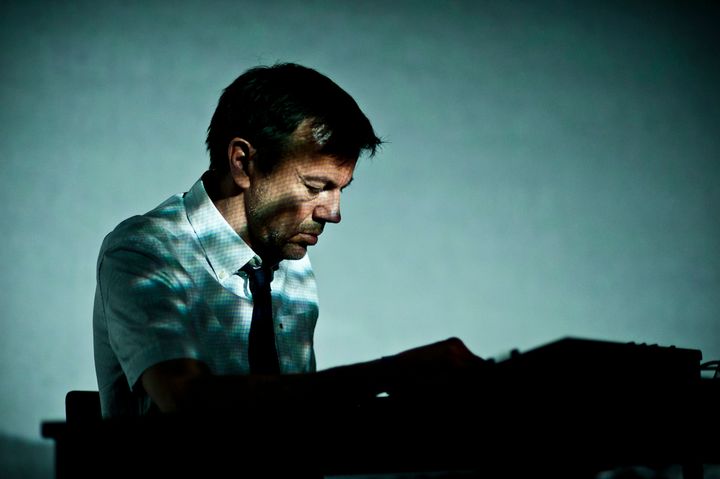 Mann spiller piano i blågrønt lys.