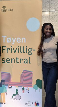 Frivillig Marcy Nyarko ved siden av roll up for Tøyen frivilligsentral