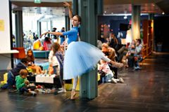 En ballerina som danser i en kafe foran barn som leker med lego