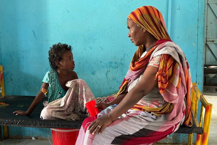 Bildet viser en mor og et barn sittende på en seng i barneavdelingen ved kolerabehandlingssenteret i Kosti, Sudan.