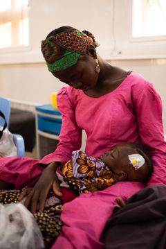 Musiaba Gidado holder rundt barnet sitt, Fatima, ved et ernæringssenter i Katsina by. Fatima er på bedringens vei, men lider av alvorlig underernæring og komplikasjoner som ødem. Det har ført til at ansiktet og beina hovnet opp og blitt svært smertefulle.