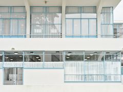 Fasade av hvit murbygning, et sanatorium med store vinduer i turkis innramming.