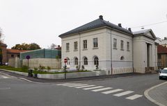 Foto av museumsbygningen vendt mot uteserveringen. En lys murbygning i klassisk stil.