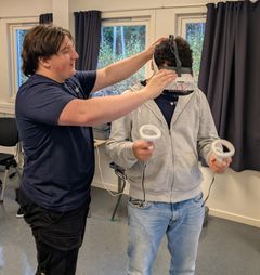 BISTÅR: Elev Jarl hjelper til å sette VR-headsettet godt på.