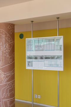 A photograph of facade of building with white, rendered walls; a sanatorium with plate-glass windows in turquoise frames placed in front of a yellow wall.