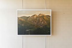 A photograph shows a mountain landscape with a tuberculosis sanatorium to the lower left, the picture is placed in front of a white wall.