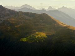 An imposing mountain range seen from Davos with many peaks, a bright sky and sunlight illuminating the valley.