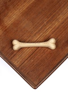 A dog bone carved in wood is placed on a table top.