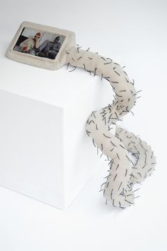 An ipad showing a video of two knitten figures sitting in a living room. The ipad is placed in a knitten cover with a long tail.