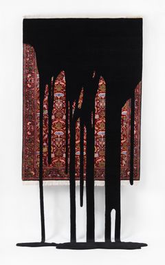 An oriental carpet hanging on the wall with black liquid running down the carpet.