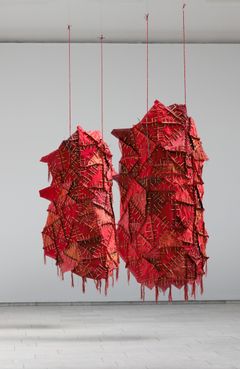 Two red objects in textile and wood hang down from the ceiling.