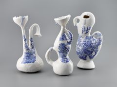 Three figures in porcelain, modelled, glazed and painted in a blue pattern resembling decorations on 19th century tableware.