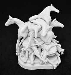 An object showing a pile of horses in molded and glazed porcelain put on top of each other.