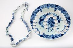 A necklace made of round circular cut outs from tableware with blue decorations.