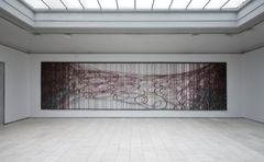A large textile work made by hand-cut, laminated wool felt and formed in a geometrical shape, where you can see the white wall through the cut outs. .