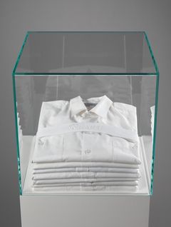 A stack of white shirts put in a glass stand.