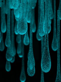 Close up of Turquoise drops of glass against a black background.