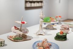Close up of a table set with plates and cake platters with food and cakes, all made of ceramics.