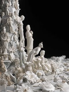 Close up of tiny figures in porcelain, persons, a cat, flowers.
