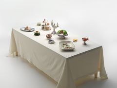A table set with plates and cake platters with food and cakes, all made of ceramics.