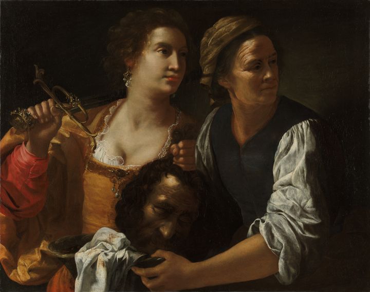 A painting showing two women, one in a yellow low-cut dress holding a sword over her right shoulder. The other is dressed in simple clothes. They hold a decapitated man's head between them, while they stand guard and look to the side.