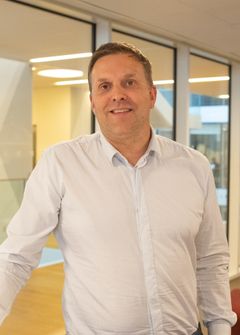 Portrett av pensjonsekspert Svein Rasmussen i SPK. Smilende mann i 50-årene med hvit skjorte.