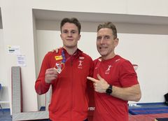 Sebastian Sponevik med gullmedaljen sammen med trener Espen Jansen.