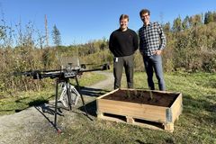 To menn står ved siden av en stor drone og en trekasse med planter.