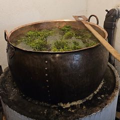 Stor kobberkjele med varmt vann og einerkvister, brukt til rengjøring og brygging.