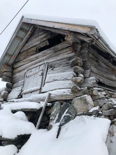 Gammelt kornhus i tømmer på Vossestrand dekket av snø.