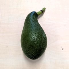 Nærbilde av en norsk avokado med mørkegrønn, ruglete skall.