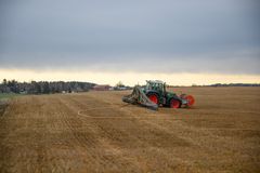 En traktor med slangespreder arbeider på et jorde under en overskyet himmel.