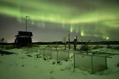 Nordlys over et snødekt forsøksfelt i Pasvik, med teknisk utstyr i forgrunnen.