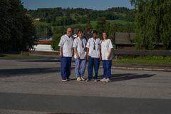 En gruppe på fire personer i uniformer står utenfor i et landskap med grønt gress og trær i bakgrunnen.