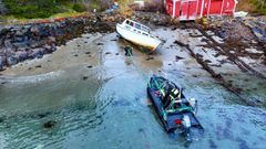 Båtvrak fjernes fra en strand i Averøy.