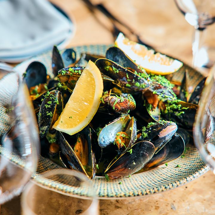 En tallerken med blåskjell pyntet med sitronbåter og hakket urter.