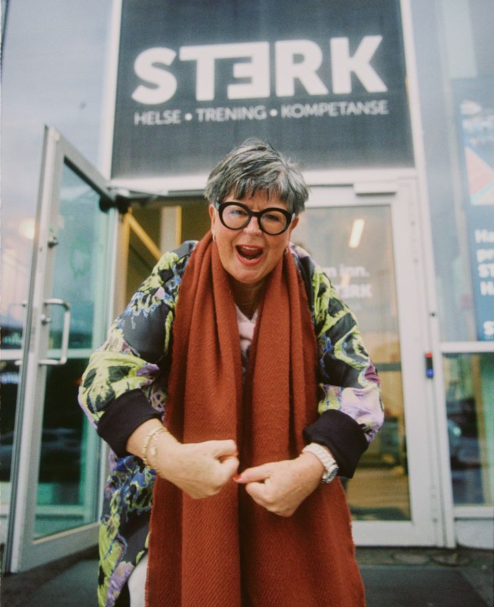 En smilende kvinne poserer foran inngangen til STERK Helse & Trening.