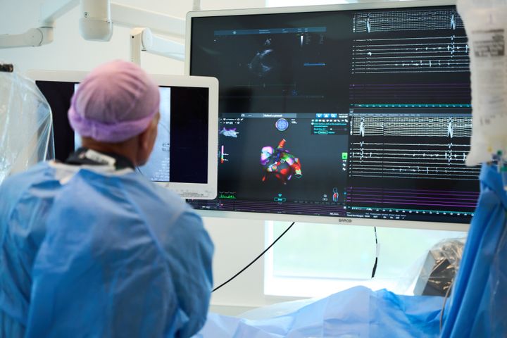 En%20person%20i%20medisinsk%20antrekk%20bruker%20Medtronic-utstyr%20under%20et%20inngrep%2C%20med%20skjermer%20i%20bakgrunnen%20som%20viser%20medisinske%20data.%20Foto%3A%20H%E5vard%20Andr%E9%20Kilv%E6r%20/%20IbsenSykehusene